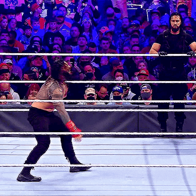 a wrestling match is going on in front of a crowd with a man wearing a shield
