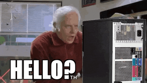 an older man is standing in front of a computer and says hello ? th