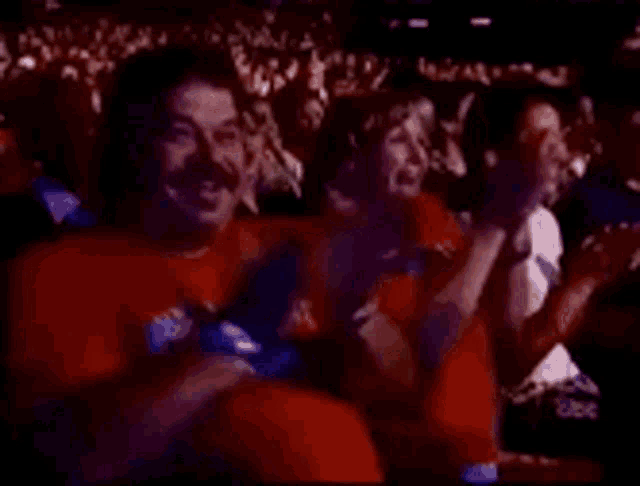 a group of people are sitting in a dark room and clapping .