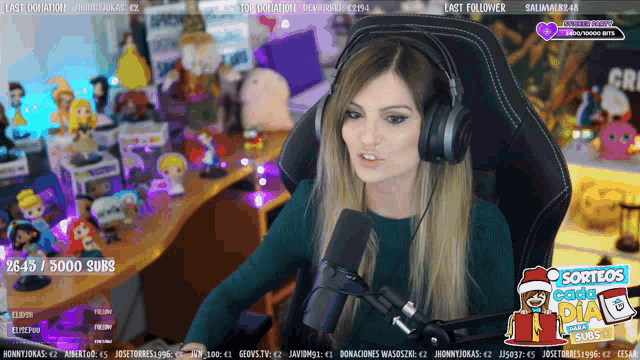 a woman wearing headphones sits in front of a microphone on a twitch channel