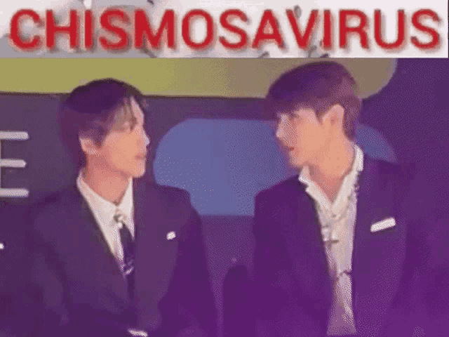 two men in suits and ties are standing next to each other and talking in front of a sign that says chismosaurus .