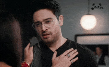 a man wearing glasses and a diamond ring is being held by a woman