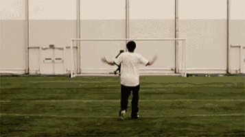a man in a white shirt is standing on a soccer field