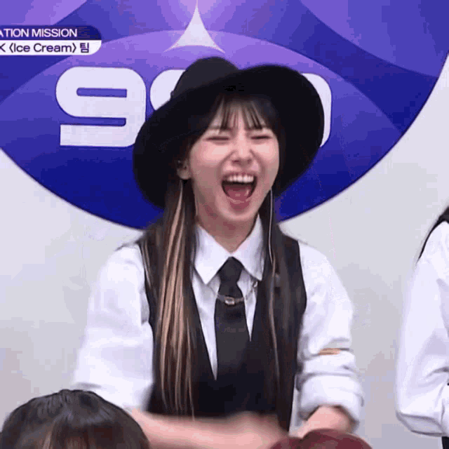 a woman wearing a hat and tie is laughing in front of a sign that says ice cream .