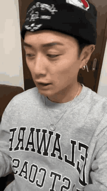 a man wearing a grey hawaii sweatshirt and a black beanie