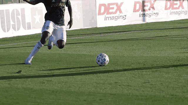 a soccer player is kicking a ball in front of a dex imaging banner