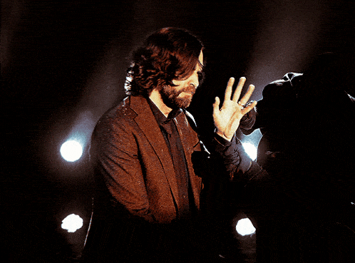 a man with long hair and a beard holds a camera in his hand