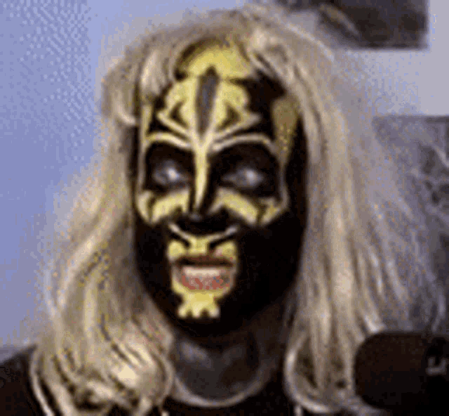a woman with long blonde hair and a black and yellow face paint is smiling .