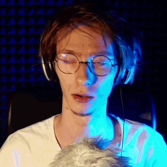 a young man wearing glasses and headphones looks at the camera