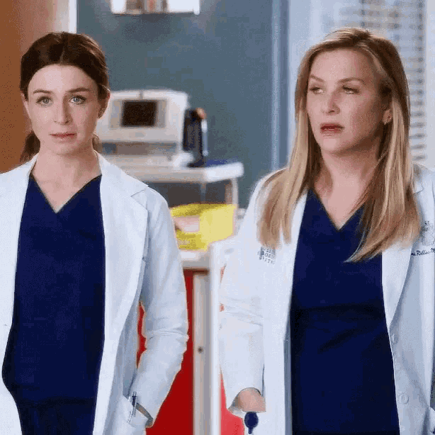 two female doctors are standing next to each other in a hospital .