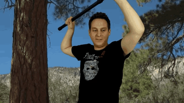 a man in a friday the 13th t-shirt holds a sword over his head
