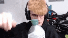 a man wearing headphones and glasses is holding a bottle of water in his hand .