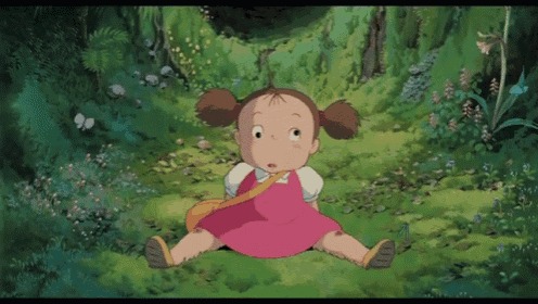 a little girl in a pink dress is sitting in the grass in a forest