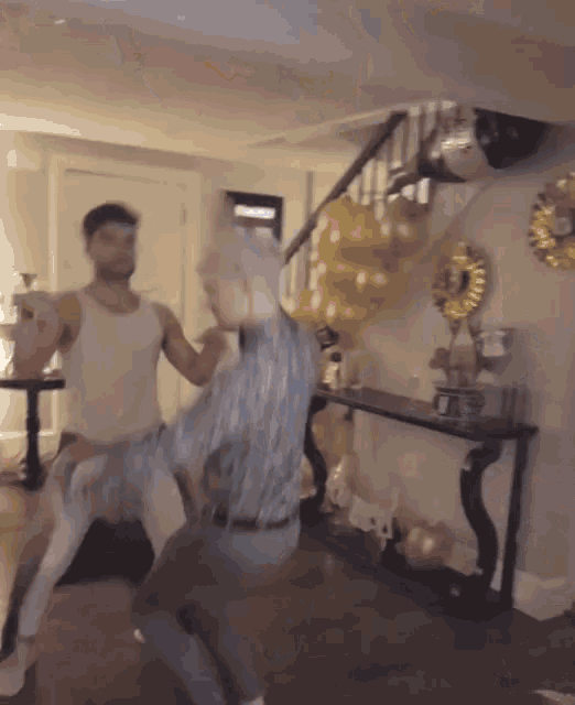 a man and a woman are dancing in a living room with balloons on the wall