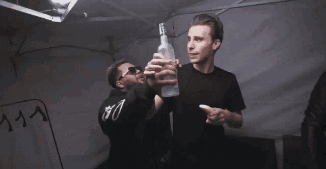 a man in a black shirt is holding a bottle of grey goose