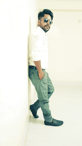 a man leaning against a wall wearing sunglasses