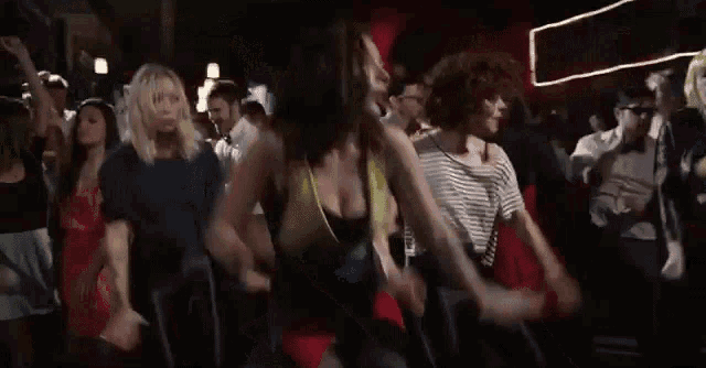 a group of women are dancing in a crowded room .