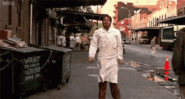 a man in a white coat is walking down a street with a green dumpster that says fast on it