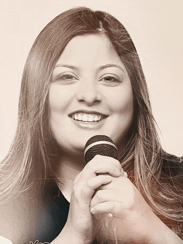 a woman is smiling and holding a microphone in her hand
