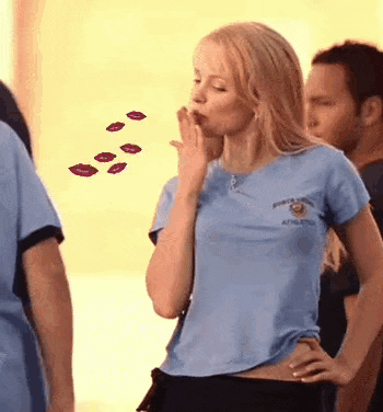 a woman in a blue shirt is blowing a kiss while standing next to a man .