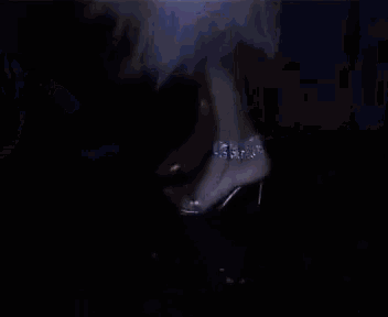 a close up of a person smoking a cigarette with smoke coming out of their mouth .
