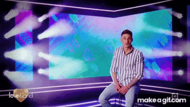 a man in a striped shirt is sitting in front of a screen that says love island