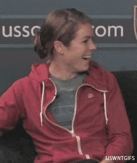 a woman is laughing in front of a sign that says uss.com