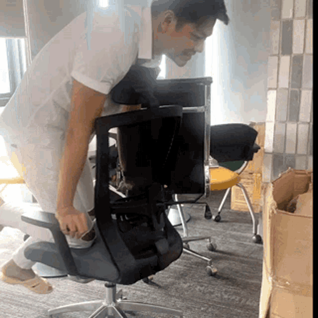 a man in a white shirt is leaning over a black chair