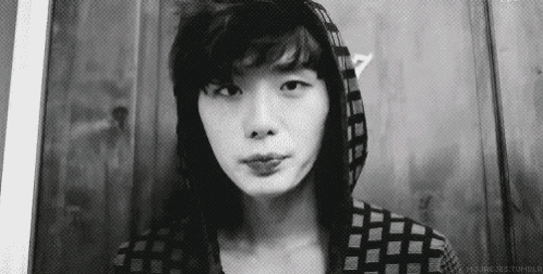 a black and white photo of a young man wearing a hoodie and making a face .