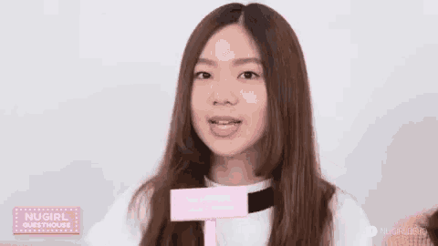 a young woman is making a funny face while holding a pink sign .
