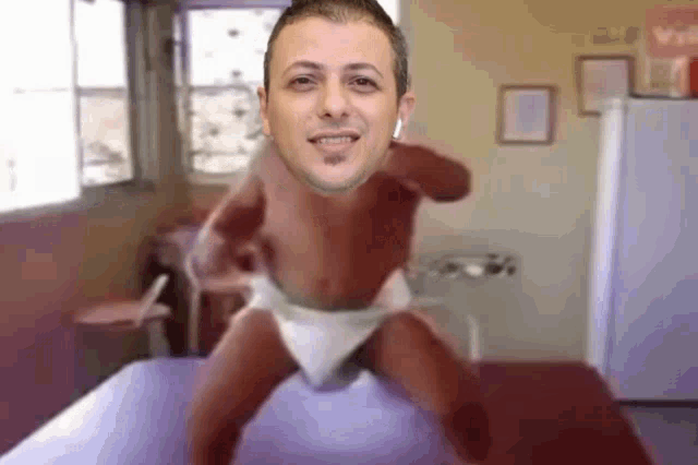 a man in a diaper is standing on a bed in a room