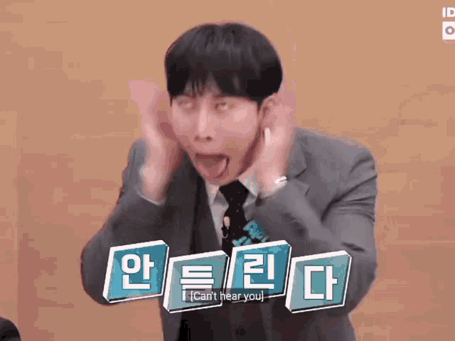 a man in a suit and tie is making a funny face with his hands on his head .