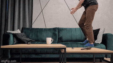 a man is jumping on a table in front of a couch