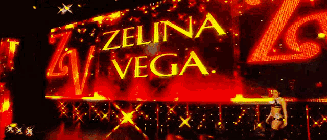 a woman stands in front of a large screen that says " zelina vega "