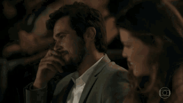 a man with a beard is sitting next to a woman who is smiling