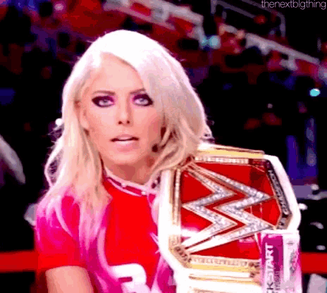 a blonde woman is wearing a pink shirt and holding a wrestling championship belt .