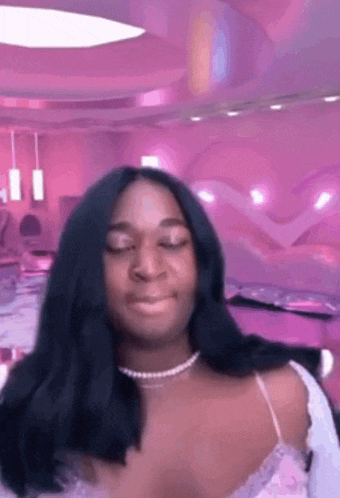a woman with long black hair is making a funny face in a purple room .