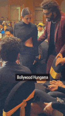 a woman in a black dress is standing next to a man in a burgundy suit and the caption bollywood hungama
