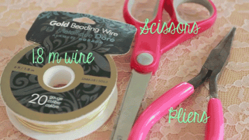 a spool of gold beading wire sits next to a pair of scissors and pliers