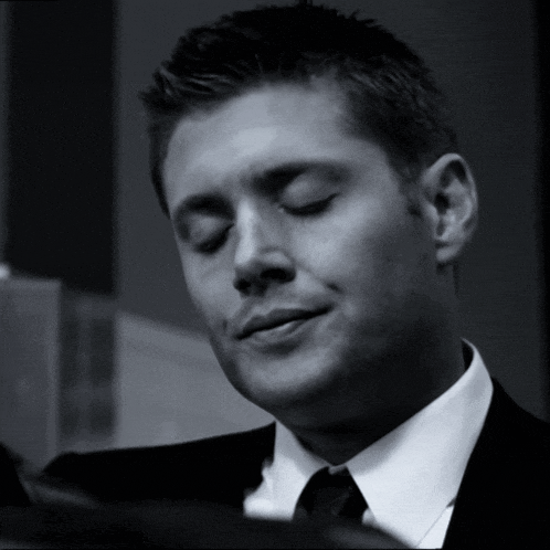 a black and white photo of a man in a suit and tie with his eyes closed