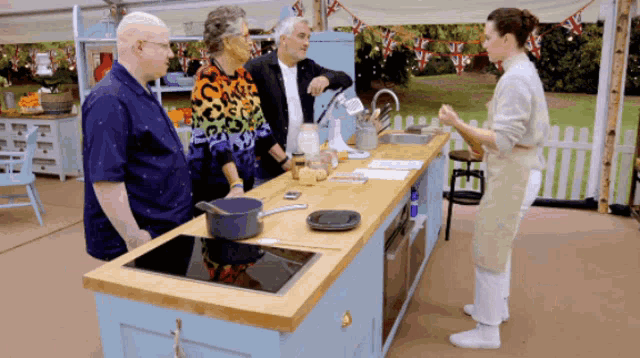 a group of people standing around a kitchen counter talking
