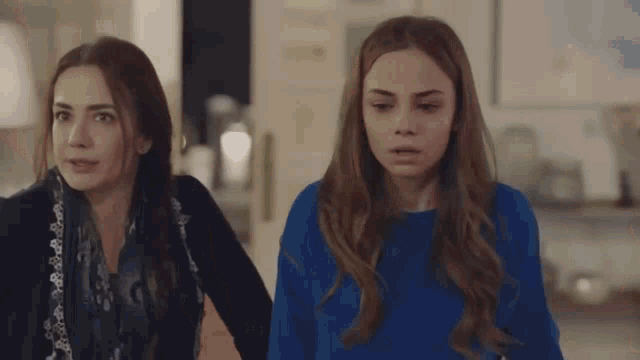 a woman in a blue sweater is standing next to another woman in a black jacket .