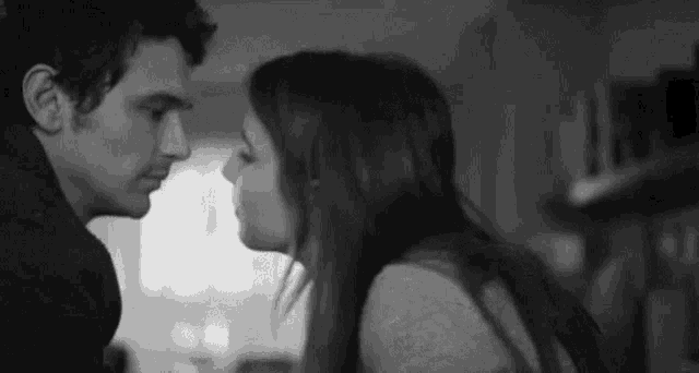 a black and white photo of a man and woman kissing each other .