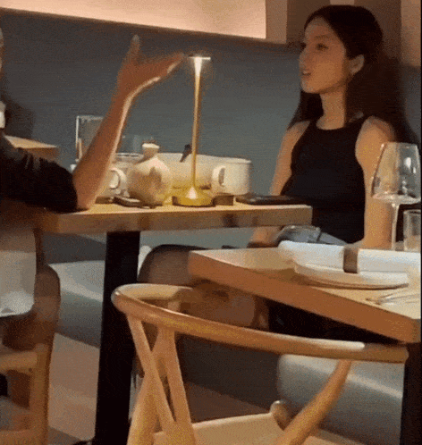 a woman sitting at a table with a man talking to her