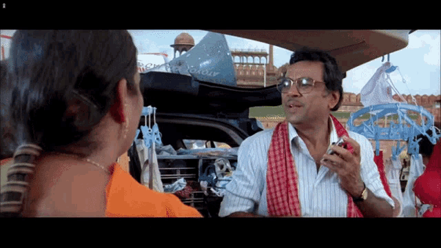 a man is talking to a woman in front of a car that says atomo
