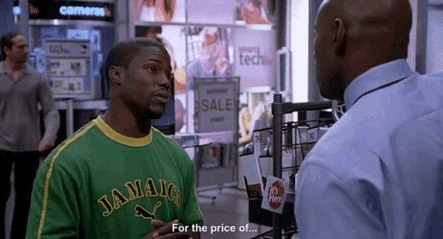 a man wearing a green jamaica shirt is talking to another man in a store .