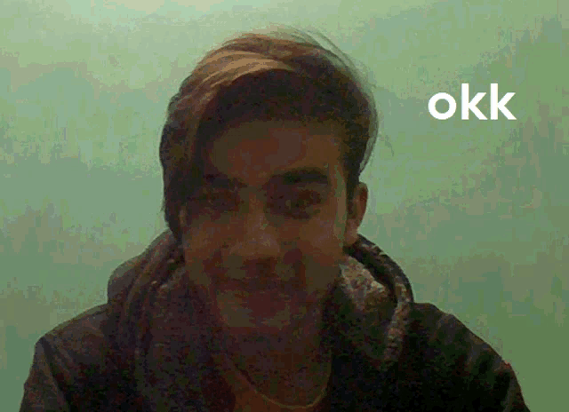 a man 's face is shown in front of a green background with the word okk written on it