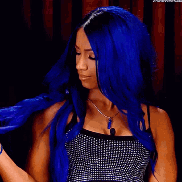 a woman with blue hair is wearing a black top and a necklace .