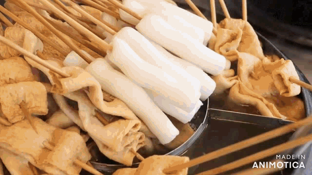 a close up of a bowl of food with sticks and rice sticks .