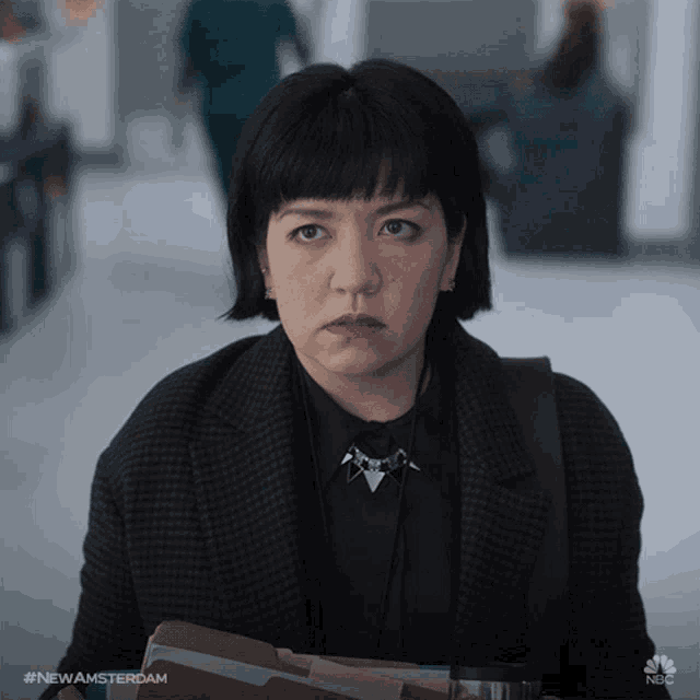 a woman is holding a folder with the hashtag #newamsterdam on it